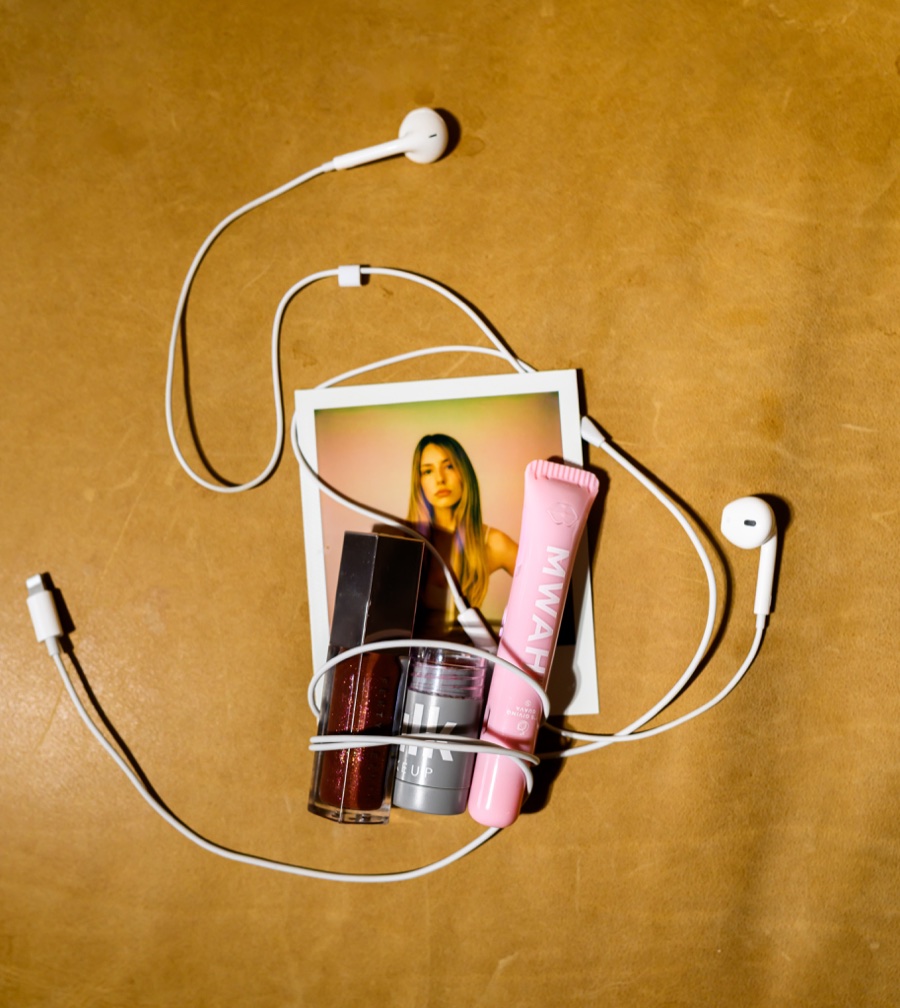 Pink MWAH vape pen styled with makeup, wired earbuds, and a fashion photograph