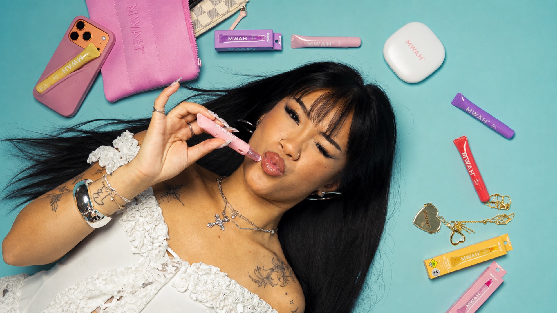 Woman holding a pink MWAH vape pen surrounded by MWAH products and accessories
